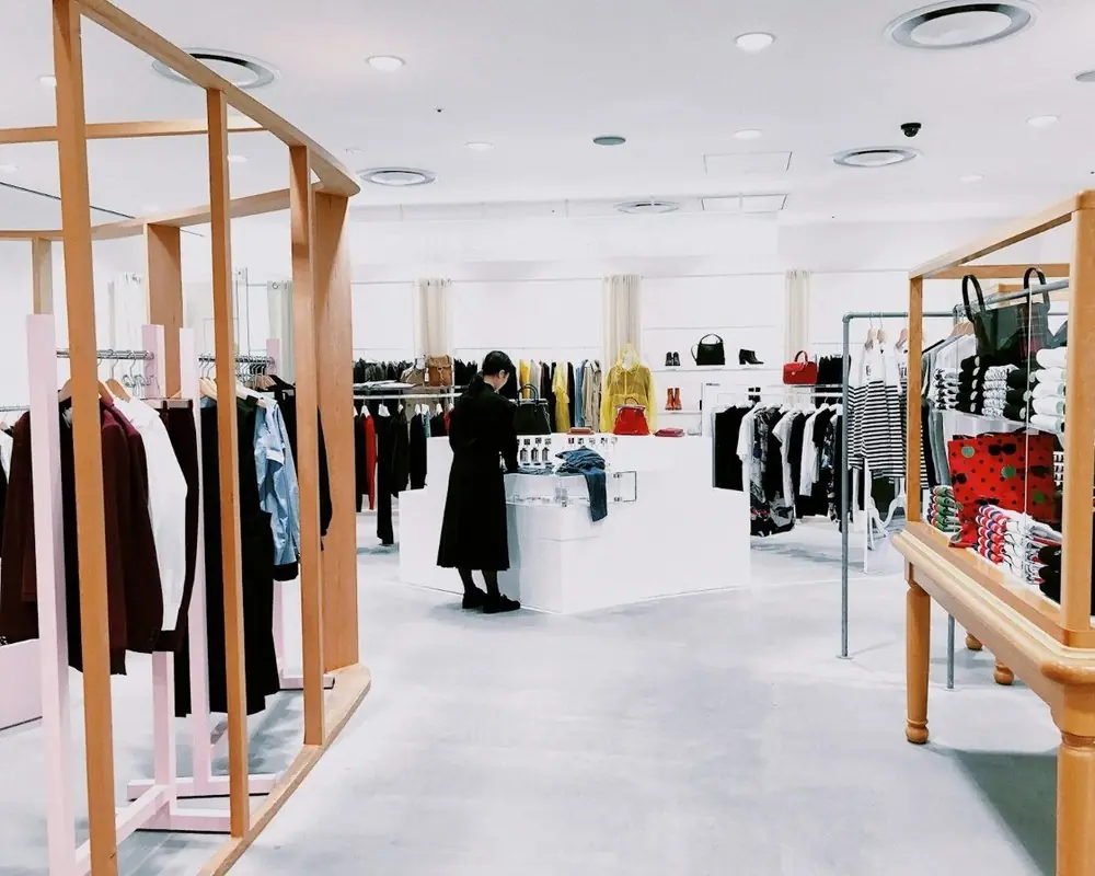 A bright clothing store with racks and display tables