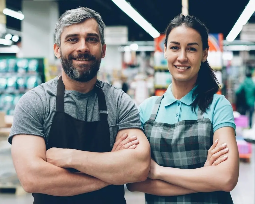 Two grocery store owners in aprons