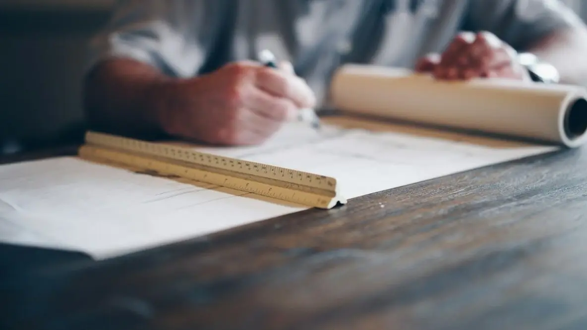 An architect drawing plans with a scale ruler