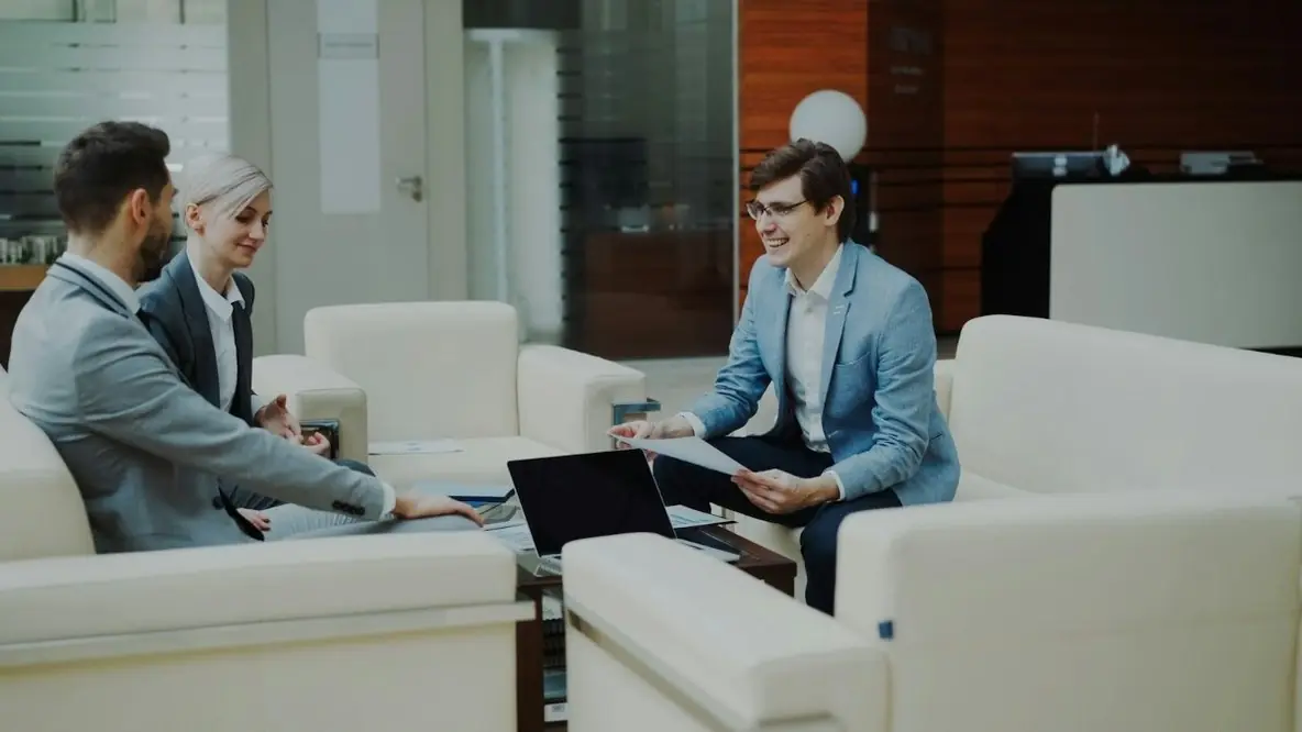 Three colleagues going over a laptop in a lounge