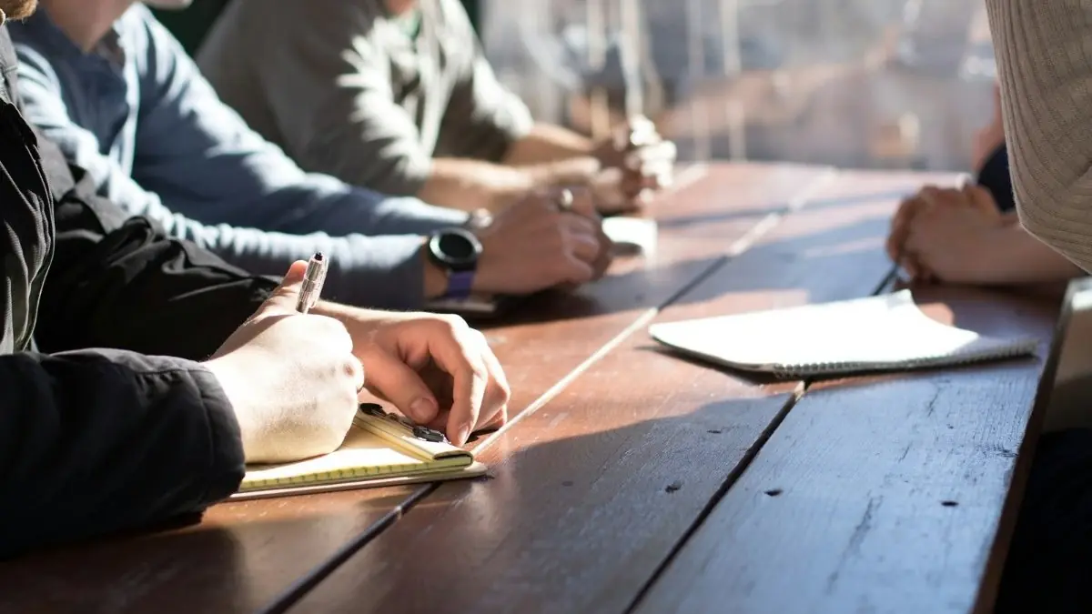 A team taking notes around a wooden table