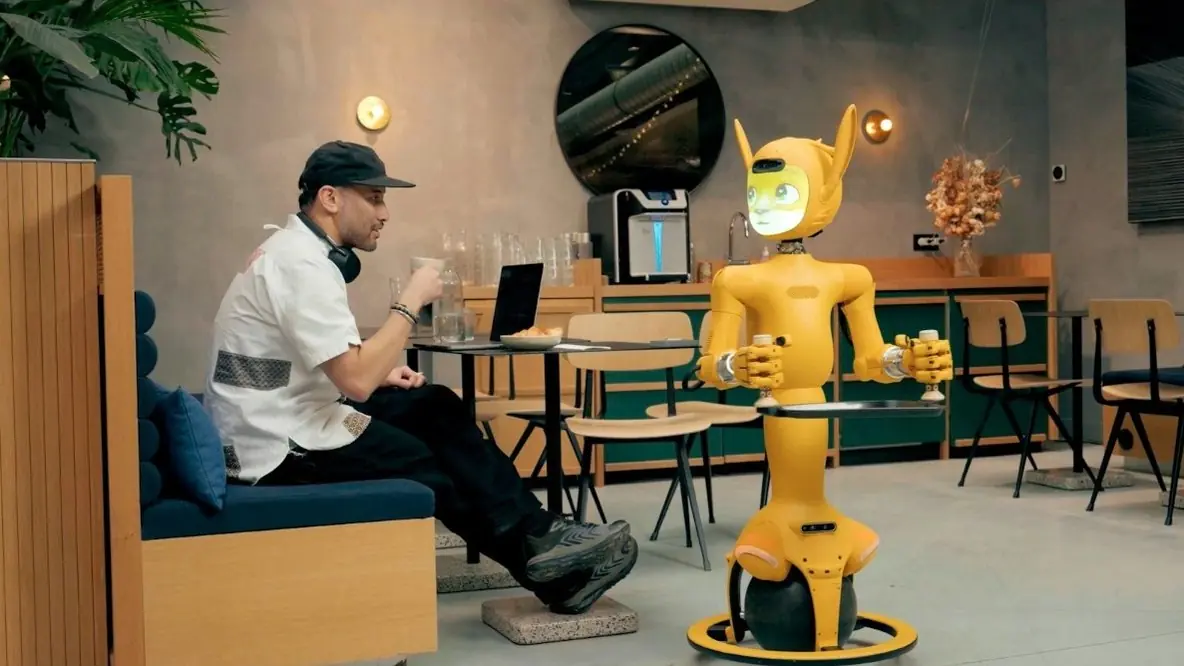 A man in a cafe next to a service robot