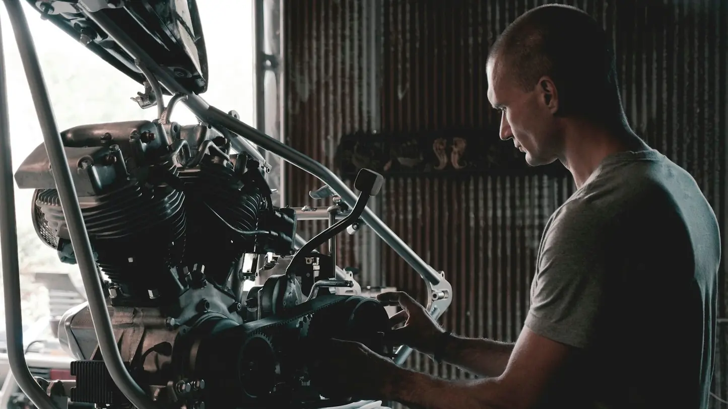 A mechanic fitting parts to a motorcycle engine in a workshop
