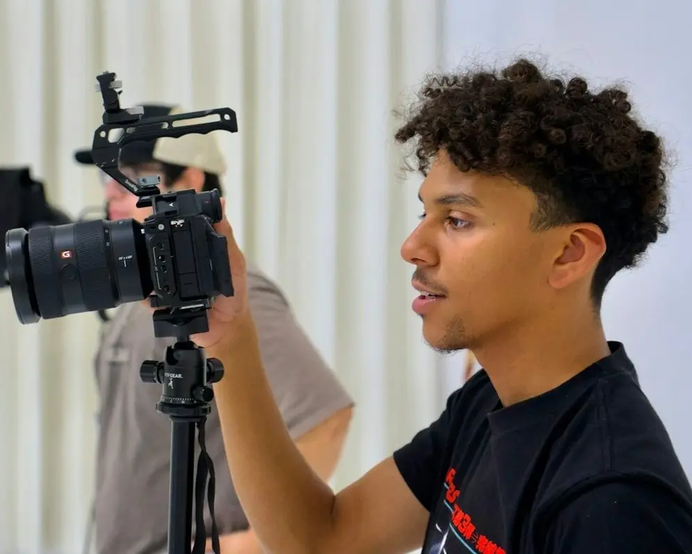 A videographer setting up a camera on a tripod