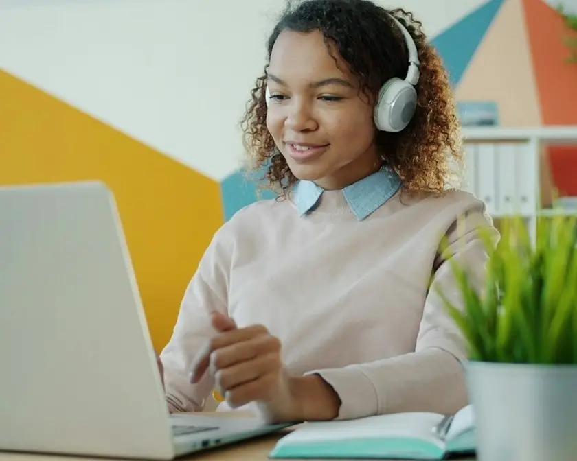 A woman in headphones working at a laptop