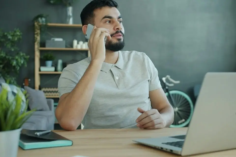 A man on a phone call at his desk