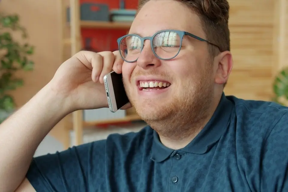 A man in glasses smiling on a phone call