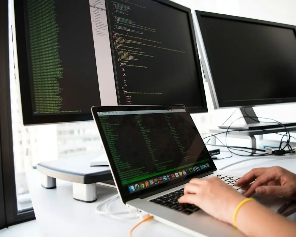 A laptop and monitors set up at a desk