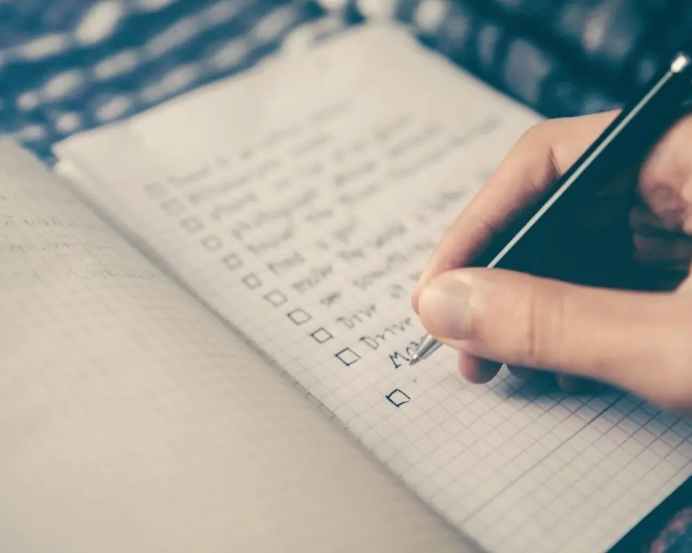 A hand ticking off a checklist in a notebook