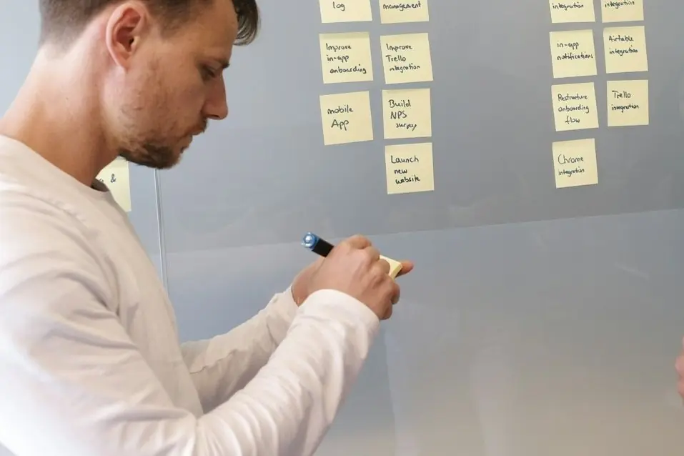 A man writing on sticky notes on a glass wall