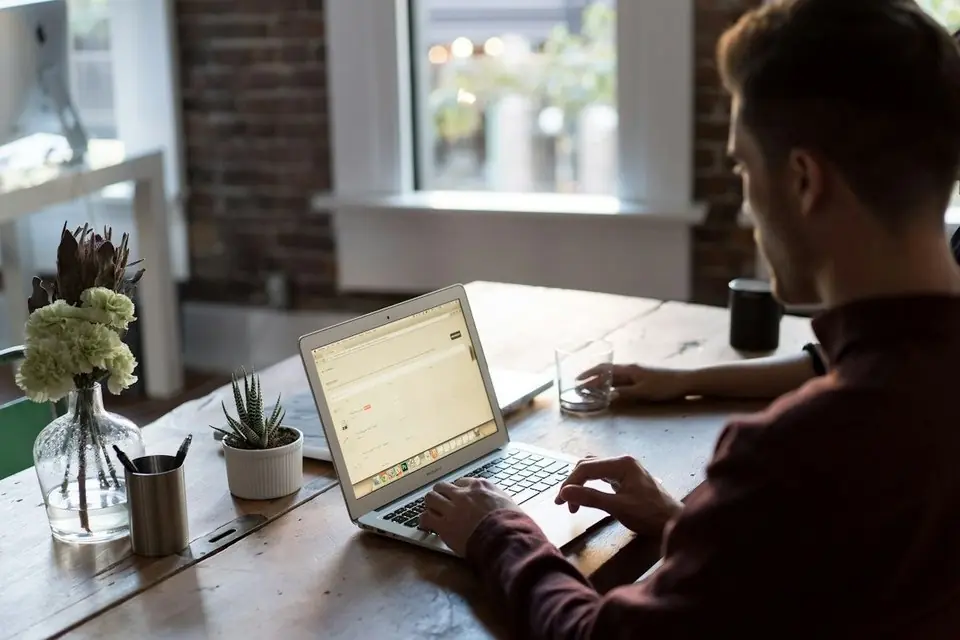 A man working on a laptop by a window