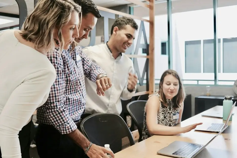 A team gathered around a laptop in an office