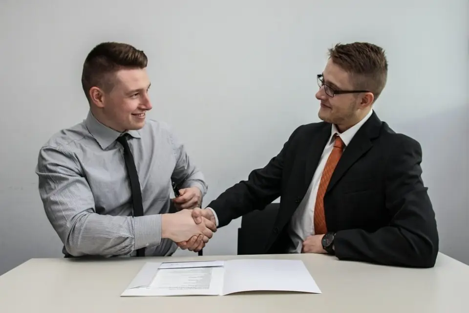 Two men shaking hands across a table