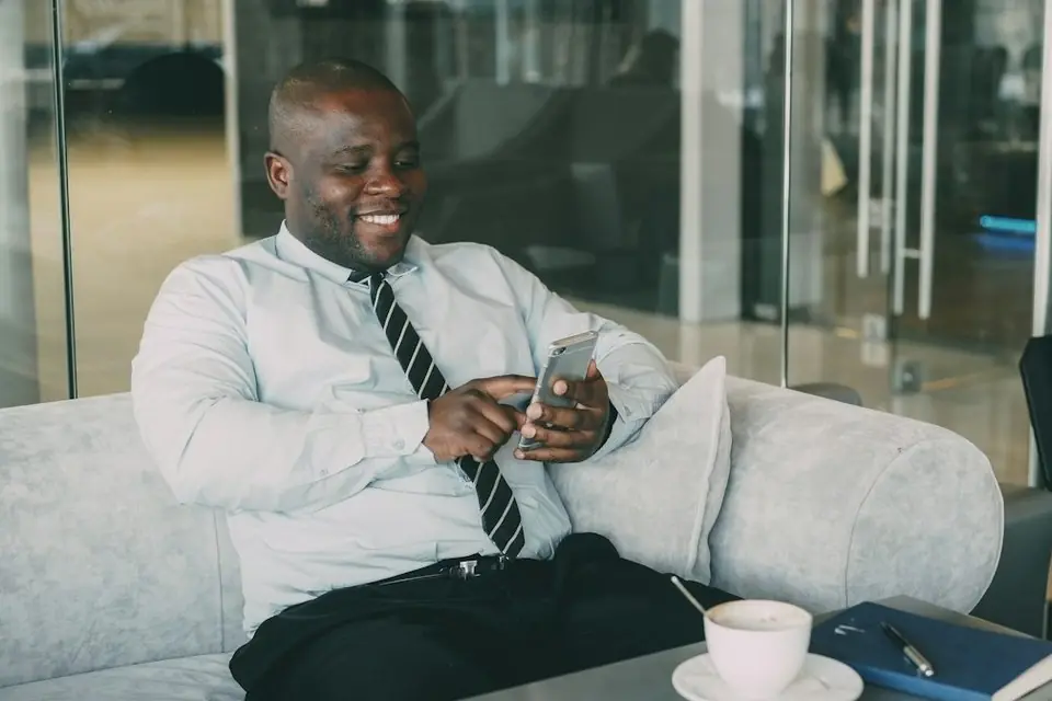 A man in a shirt and tie smiling at his phone