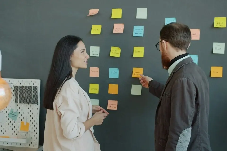 Two colleagues planning at a wall of sticky notes