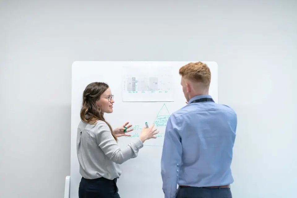 Two colleagues talking at a whiteboard