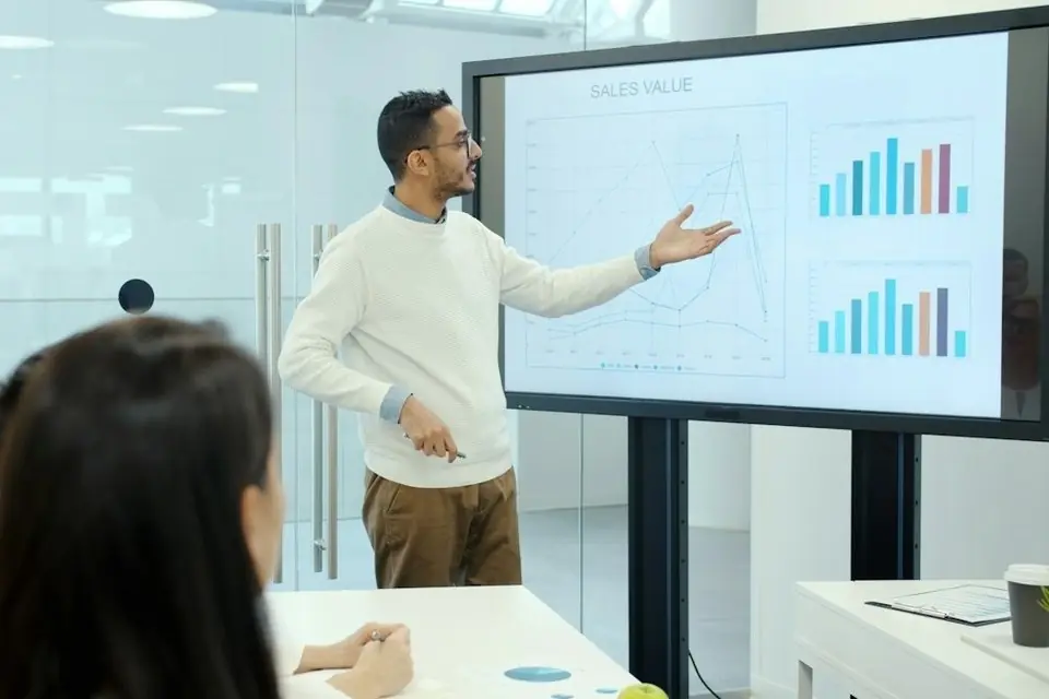 A man presenting charts on a large screen