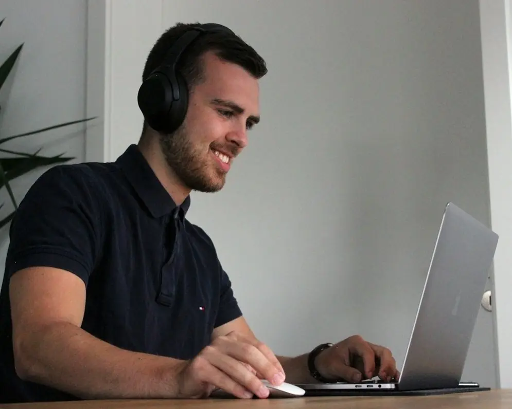 A man in headphones smiling at his laptop