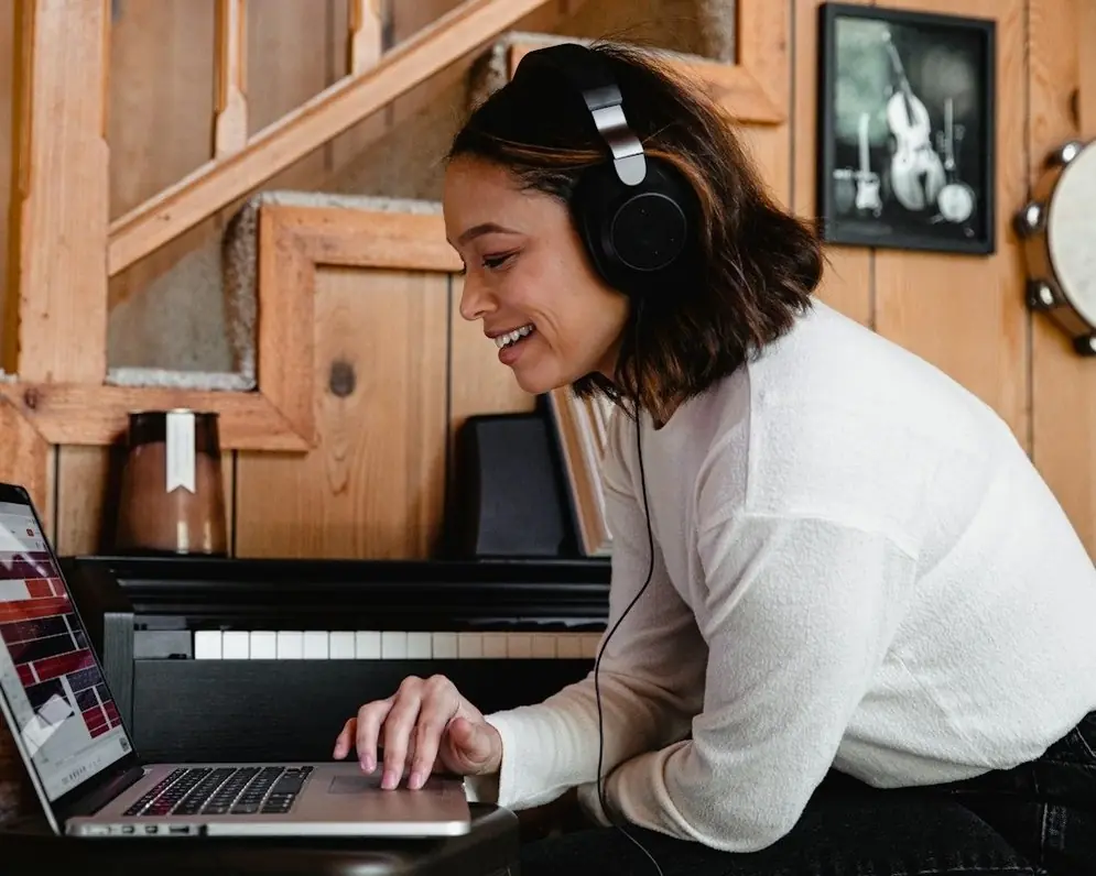 A woman in headphones smiling at her laptop