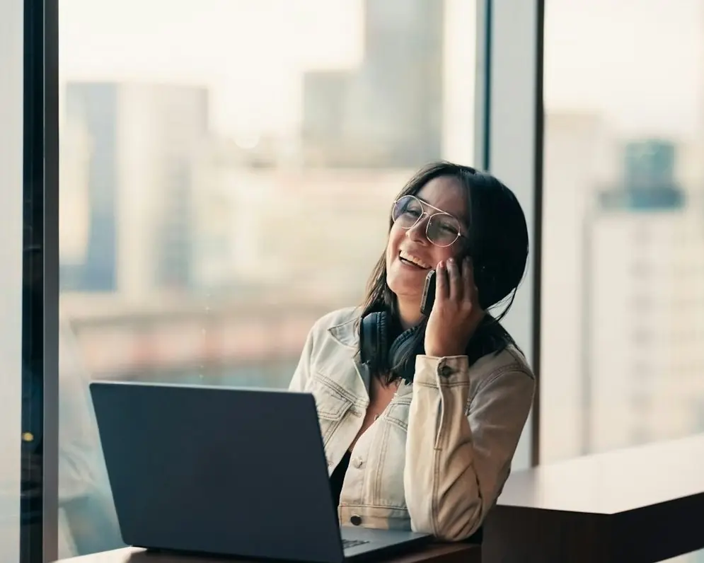 A woman laughing on a call at her laptop