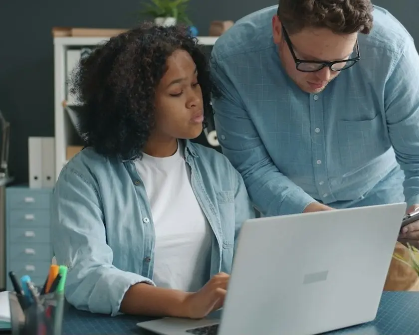 Two colleagues working through a problem at a laptop