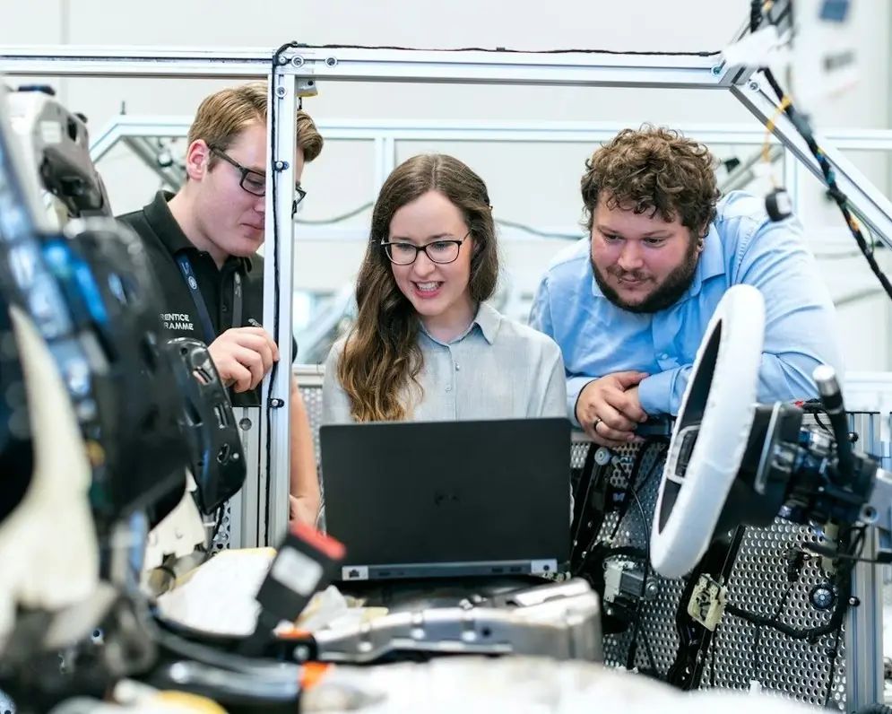Three engineers at a laptop in a hardware lab