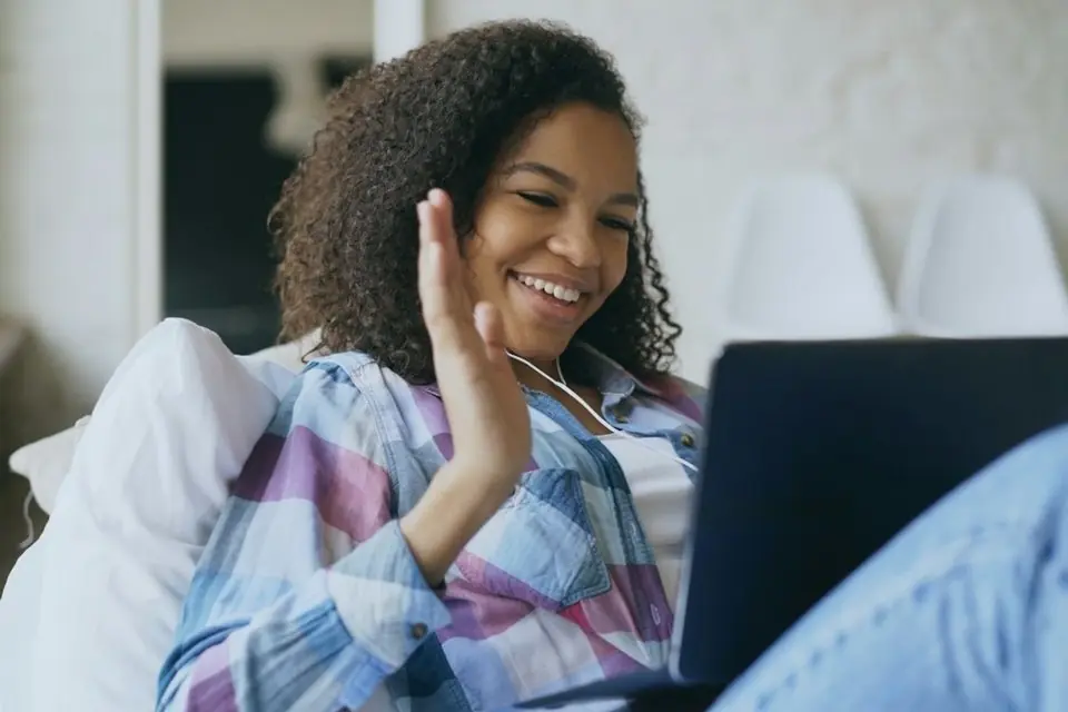 A woman smiling and waving on a video call